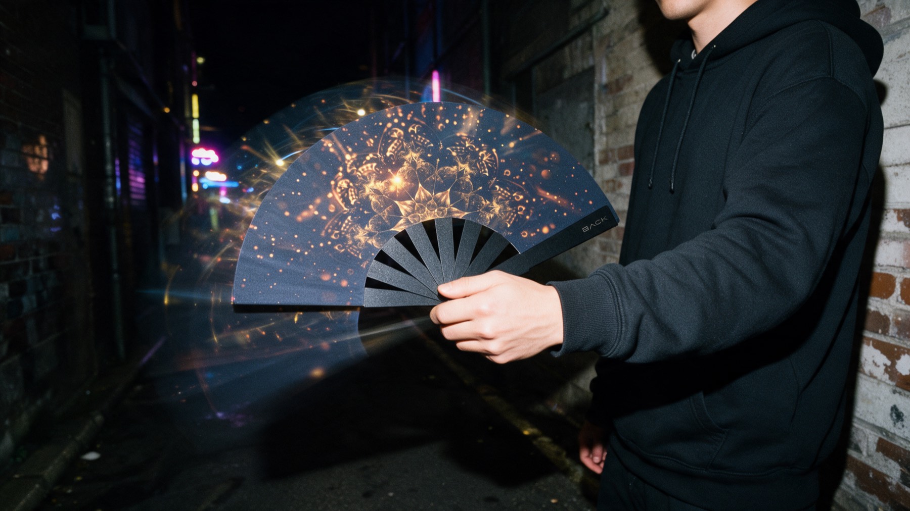 Un abanico BACK Radhi en movimiento, nítido por el flash y con una estela de luz, en un callejón de noche